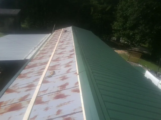 Old rusted panels beside newly installed green metal roofing — Wind Damage Roof Repair by Roofing Brothers in Edgar